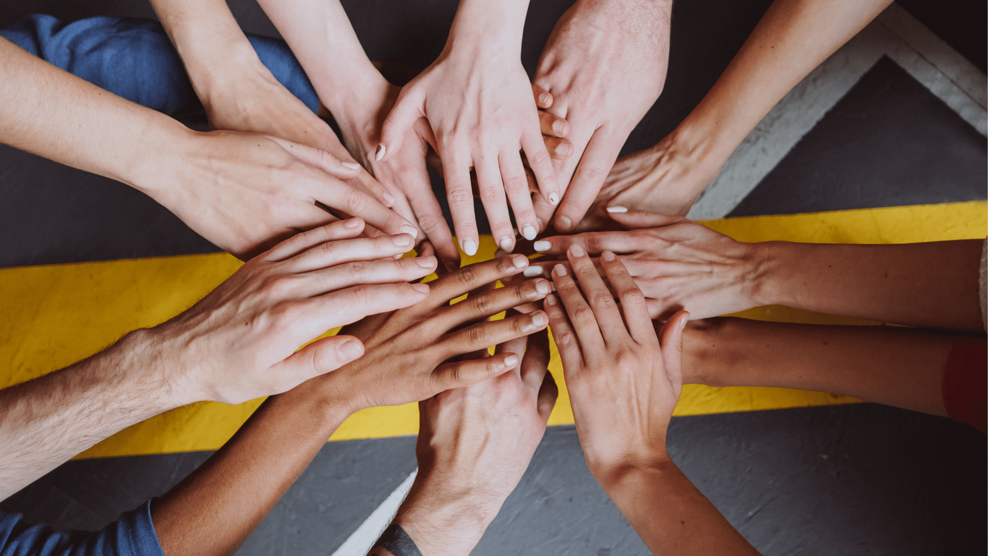 Diverse group of people holding there hands together in a central focal point.