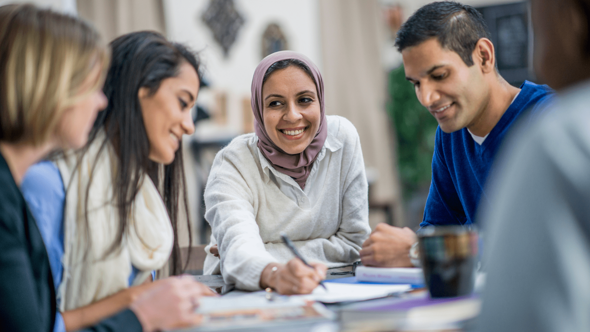 Diverse group of people sitting at a table talking and smiling.