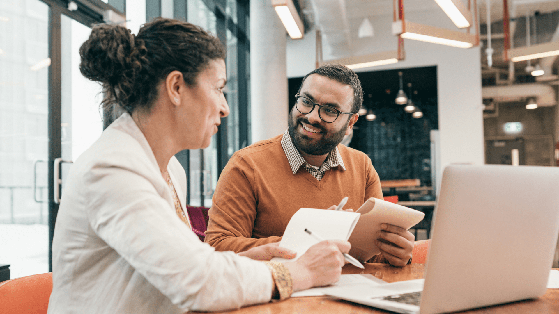 Image of two people sitting at a table talking.