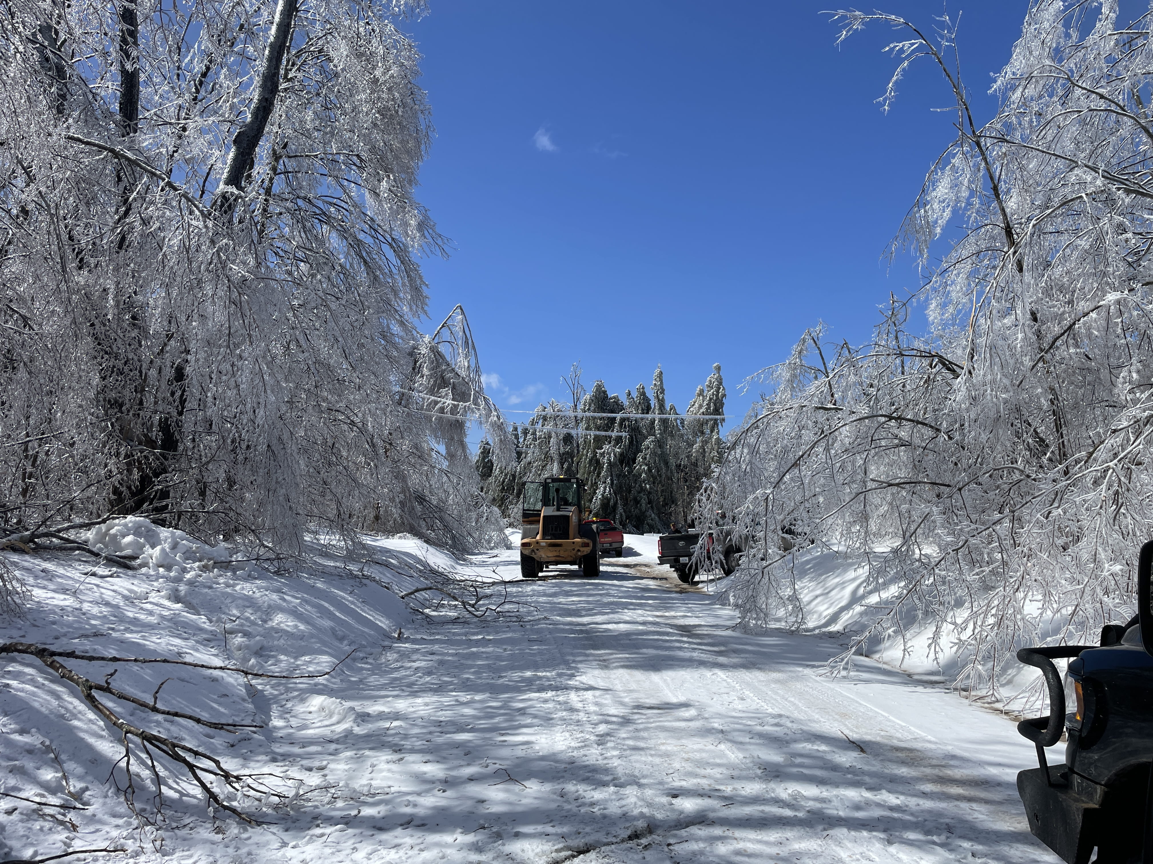 Heavy machinery driving down a snow and ice covered road.