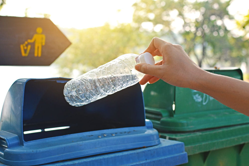 Image of person throwing a plastic bottle into a recycling bin