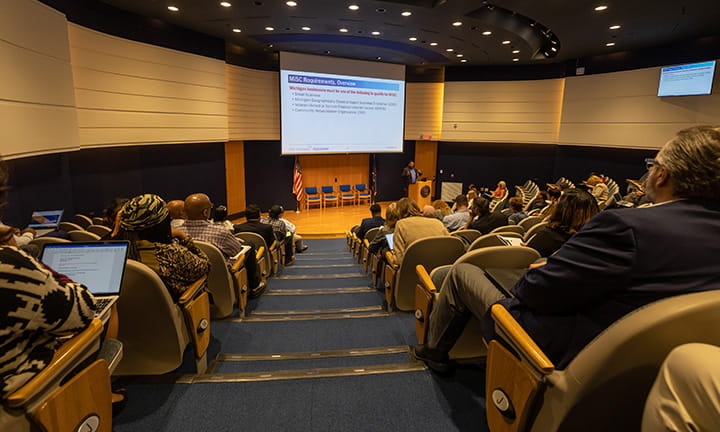 people sit in the auditorium at the Michigan Historical Center and listen to a Contracting 101 prestentation