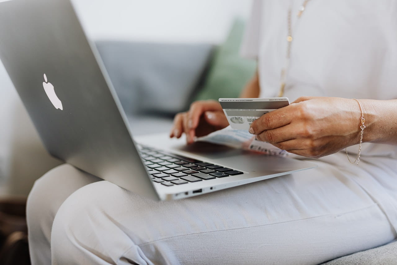 Person on laptop with credit card in one hand.