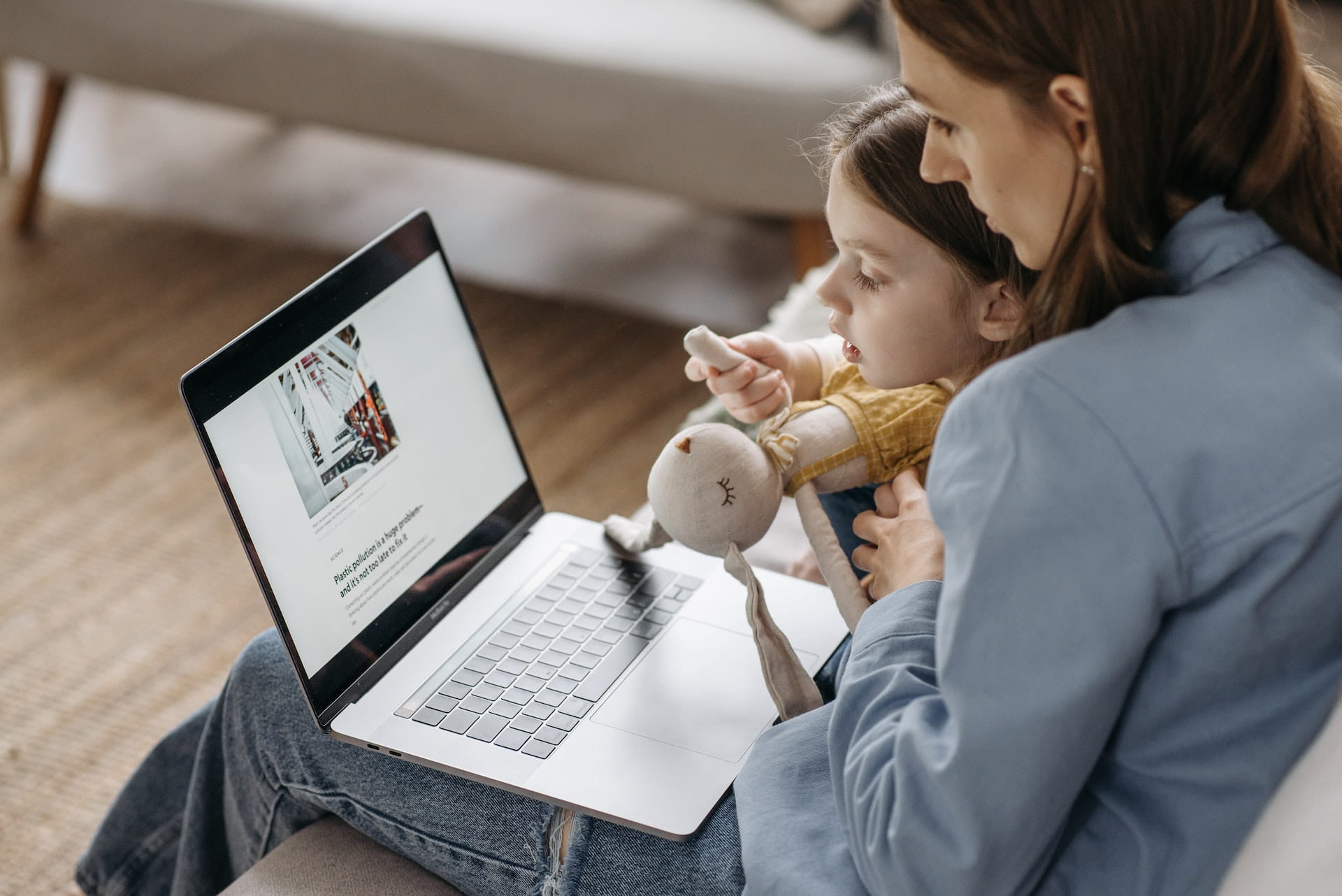 Woman and child sitting on sofa looking at a laptop.