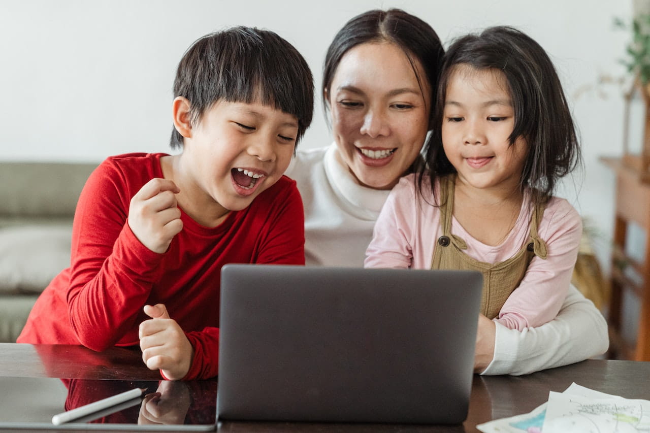 Parent and two children looking at laptop.