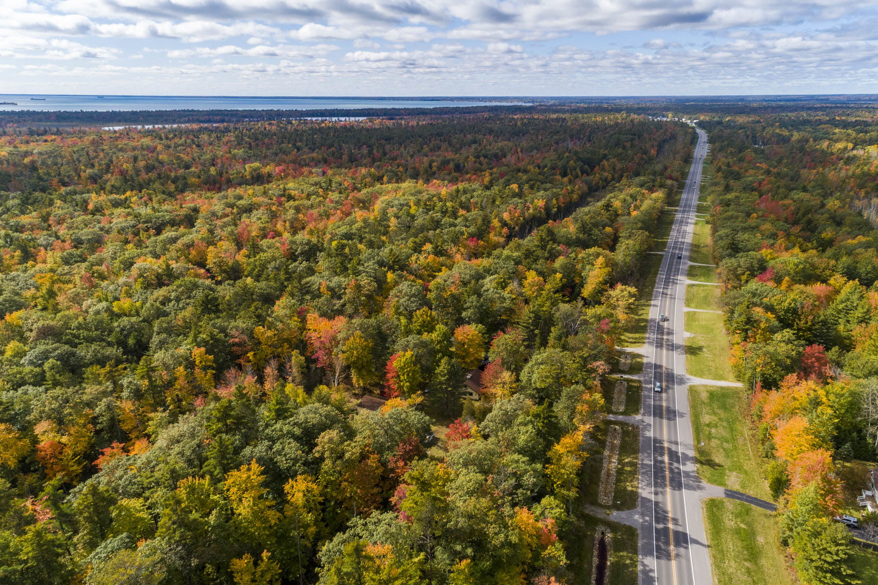 aerial view of US-23 road north of East Tawas in fall, cars travelling along road and fall trees in background
