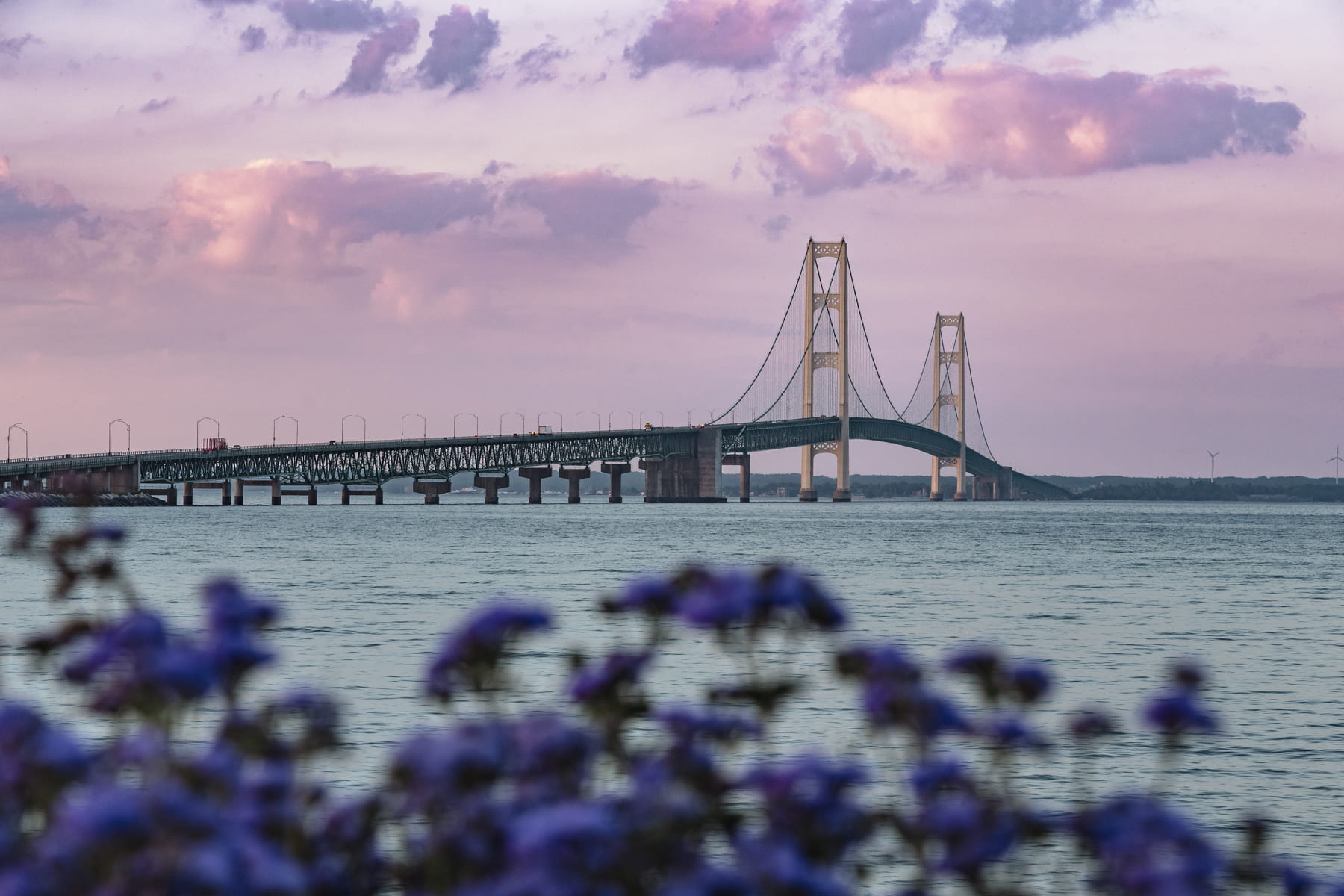 photo of mackinac bridge at sunrise - view of bridge over water and purple colored sky 