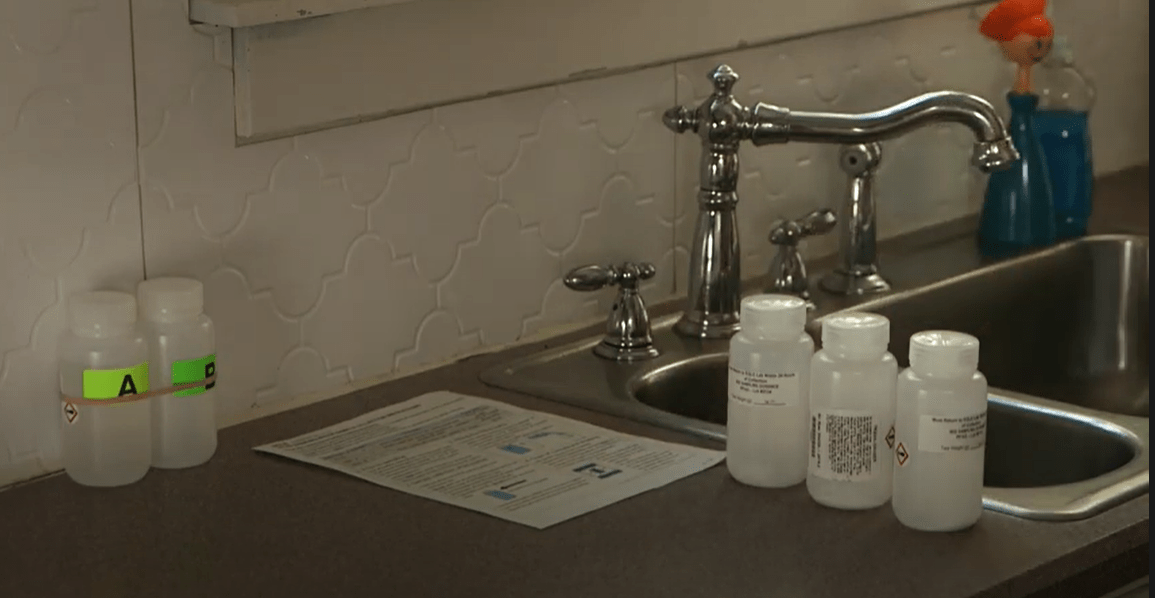 A PFAS home sampling kit set out on a kitchen counter next to a sink