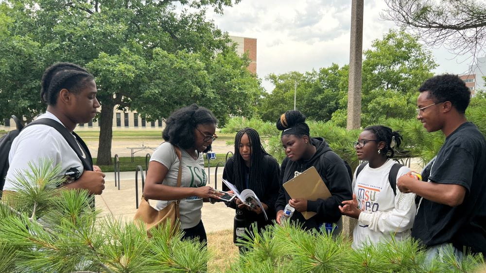 A professor explains concepts to students holding notebooks