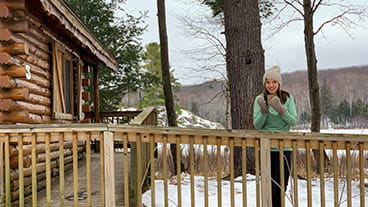 woman standing on cabin ramp drinking coffee