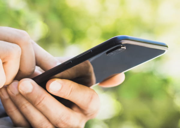 Closeup of a person's hands using a cell phone in the outdoors. 