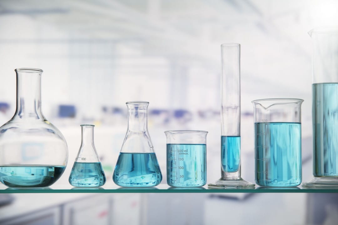 a glass shelf with beakers and graduated cylinders of various shapes and sizes placed on it