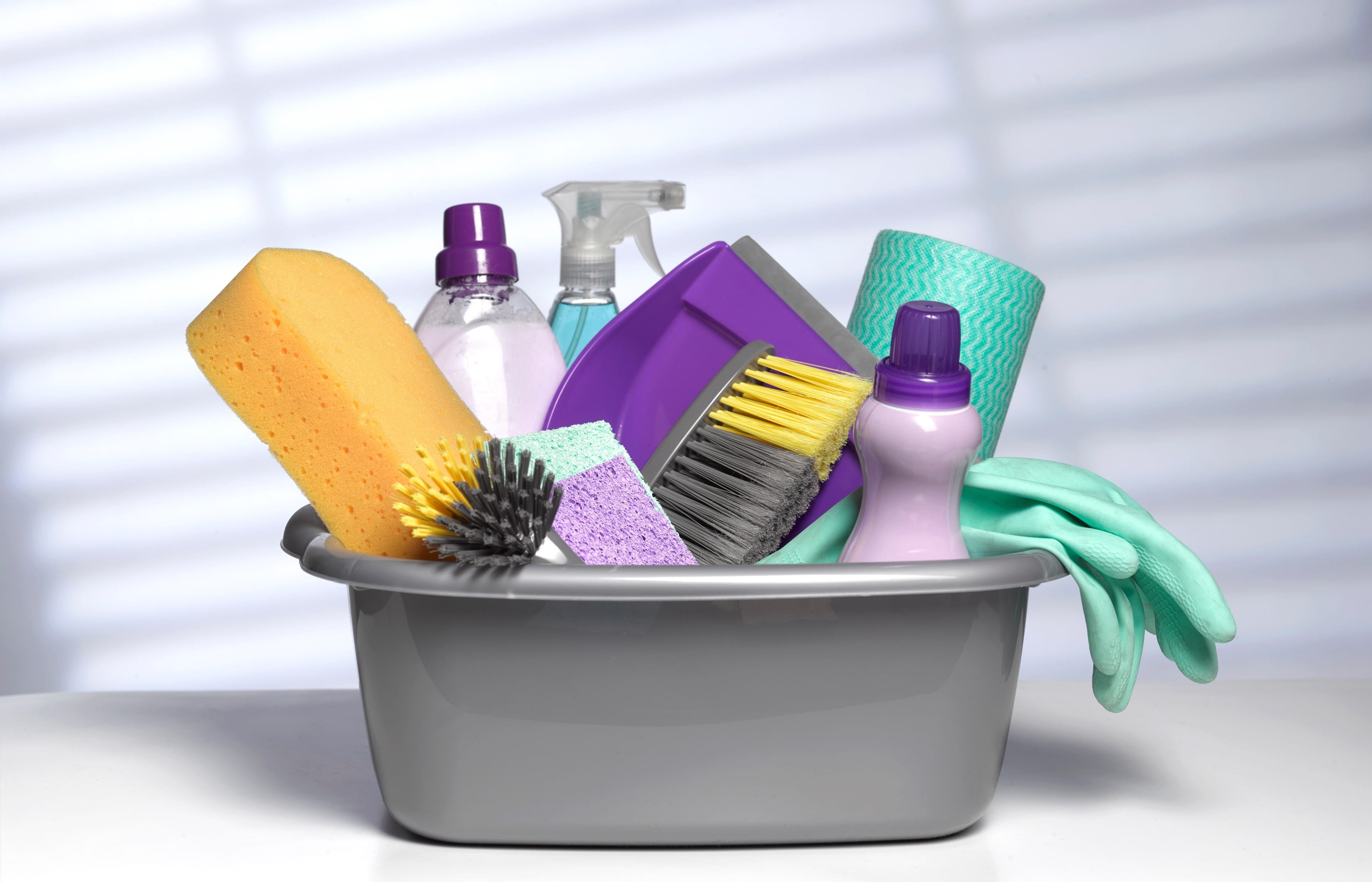 a small plastic tub filled with cleaning products, sponges, and rubber gloves