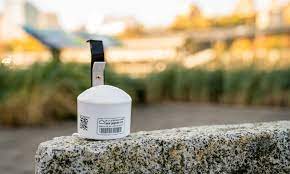A small white metal canister (a PurpleAir Monitor) nailed to a wall.