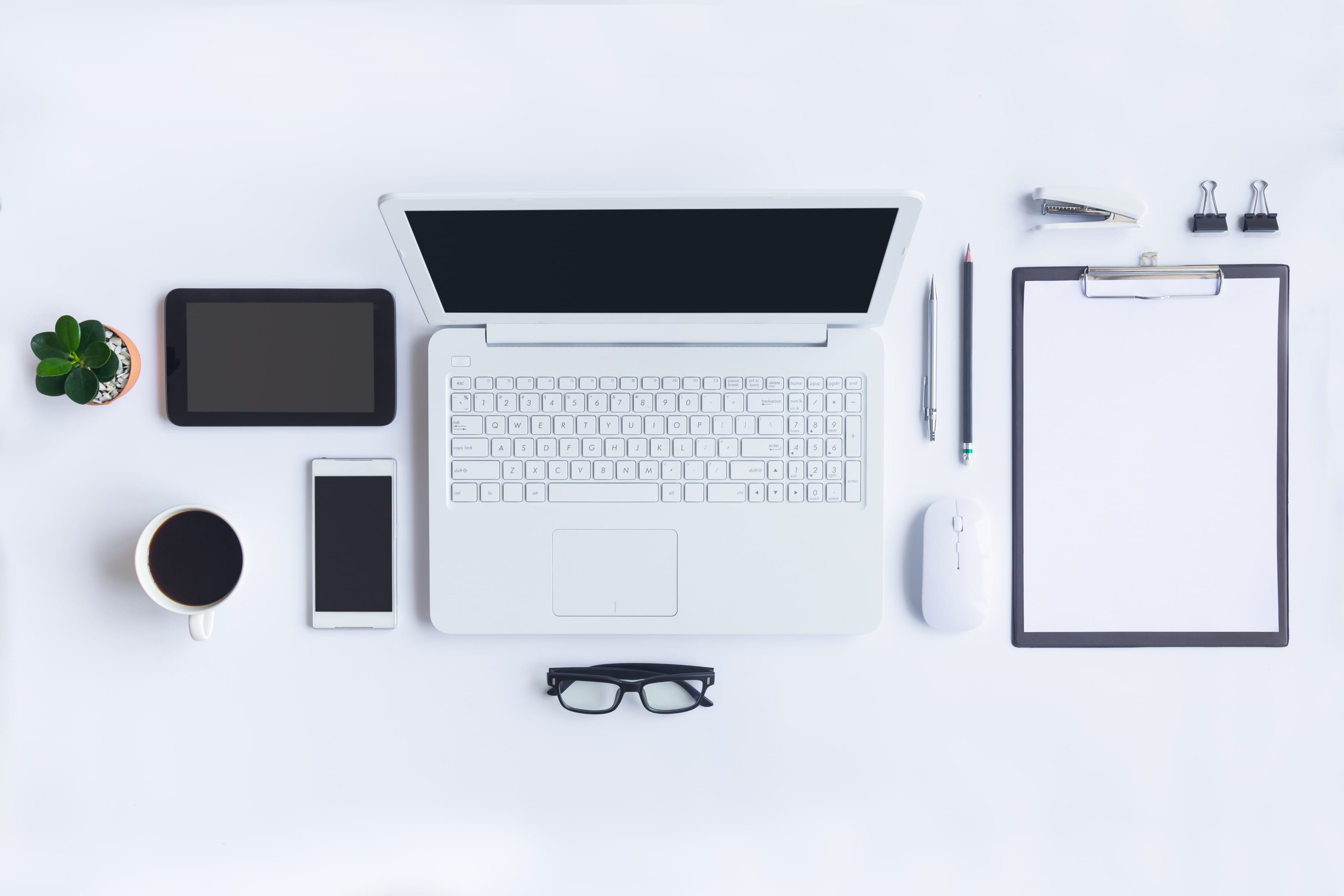 A desk with a laptop computer, notepad, calculator, and other items for work