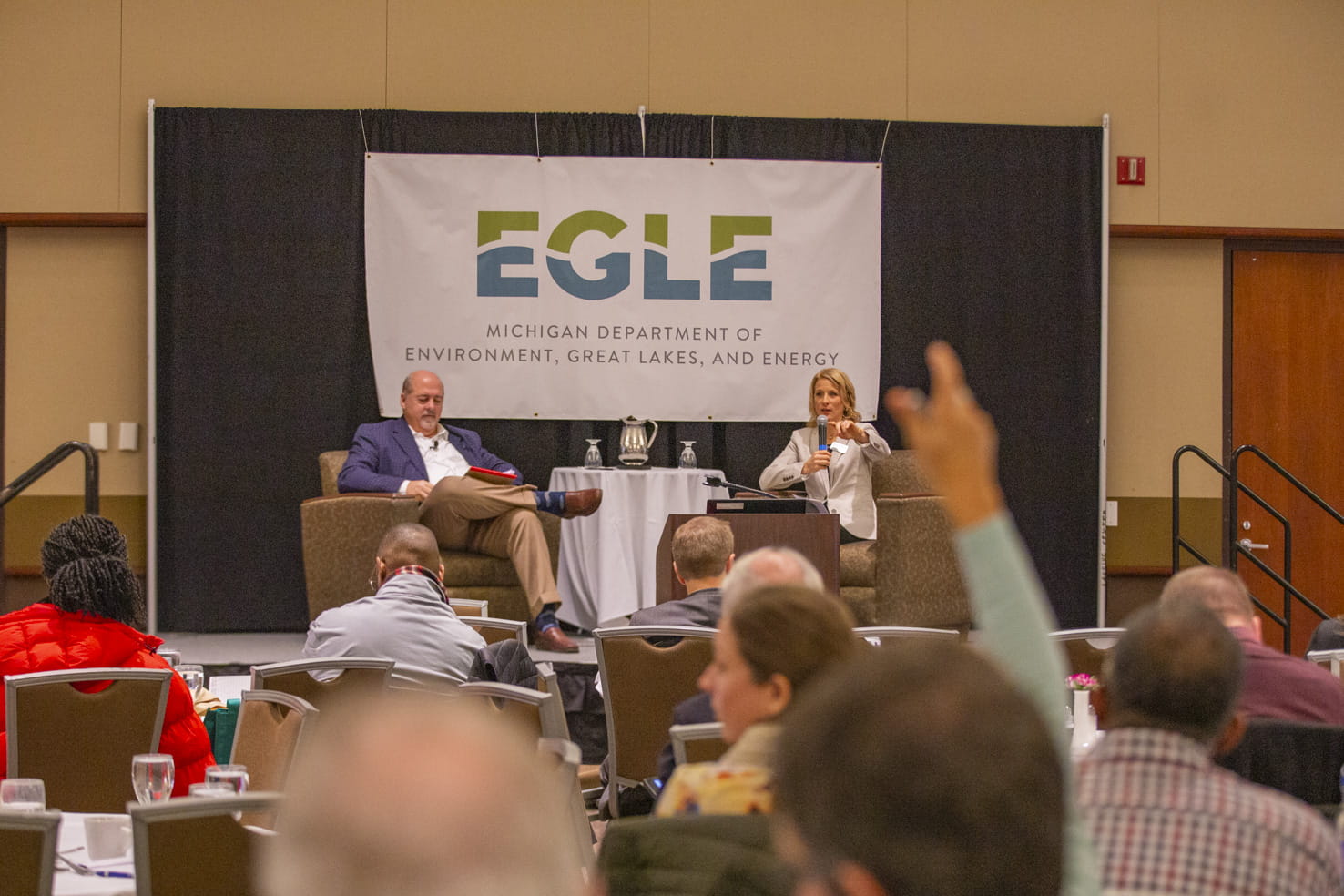 Audience member raises hand at an EGLE public meeting
