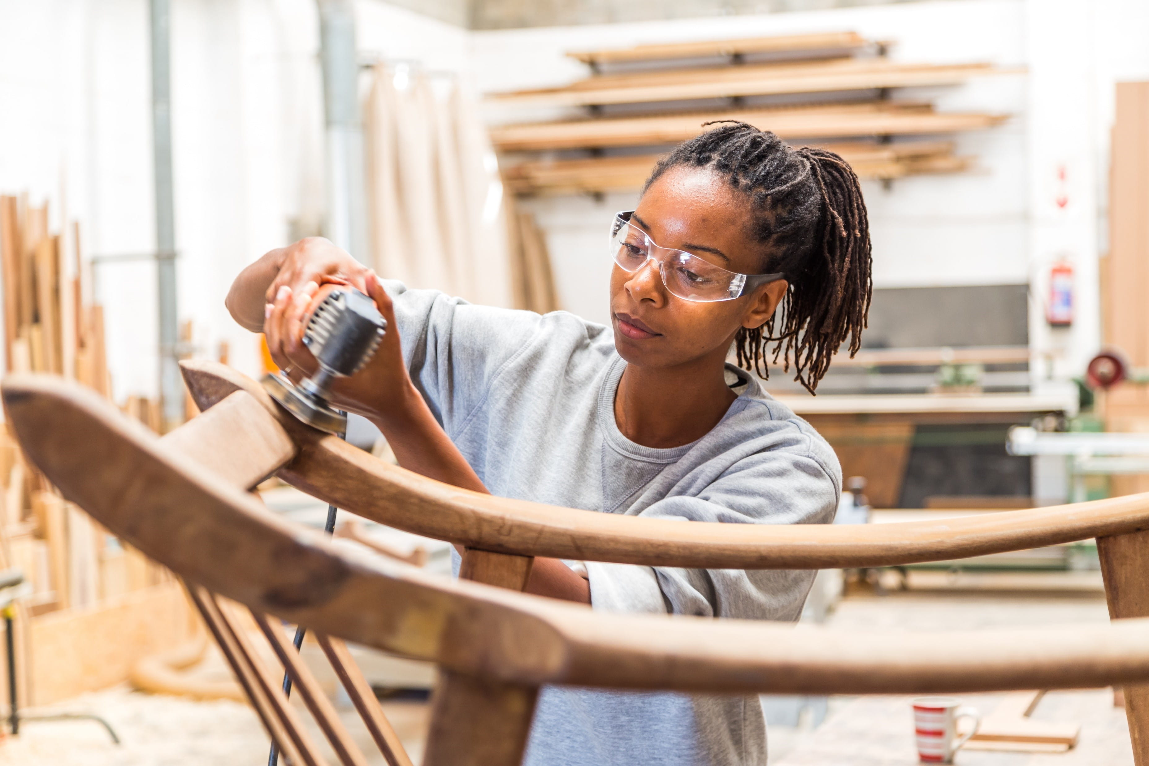 a carpenter sands the bottom of a rocking chair