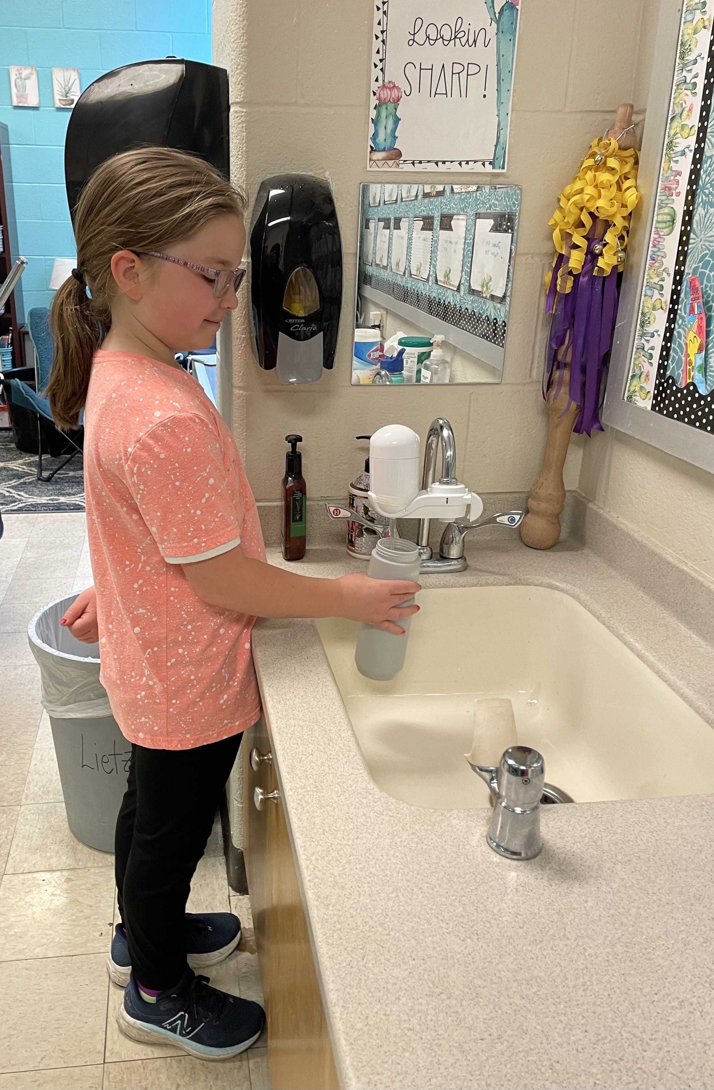 Girl filling a water bottle from a filtered faucet.