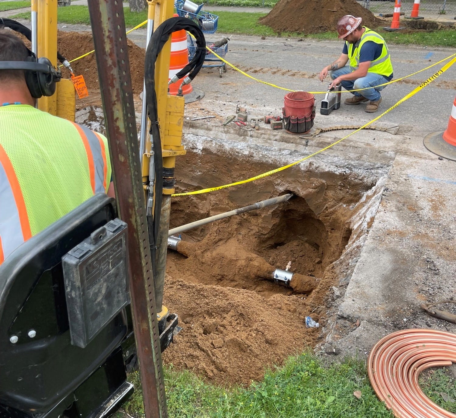 Construction works focusing on a hole in the street showing a service line dug up