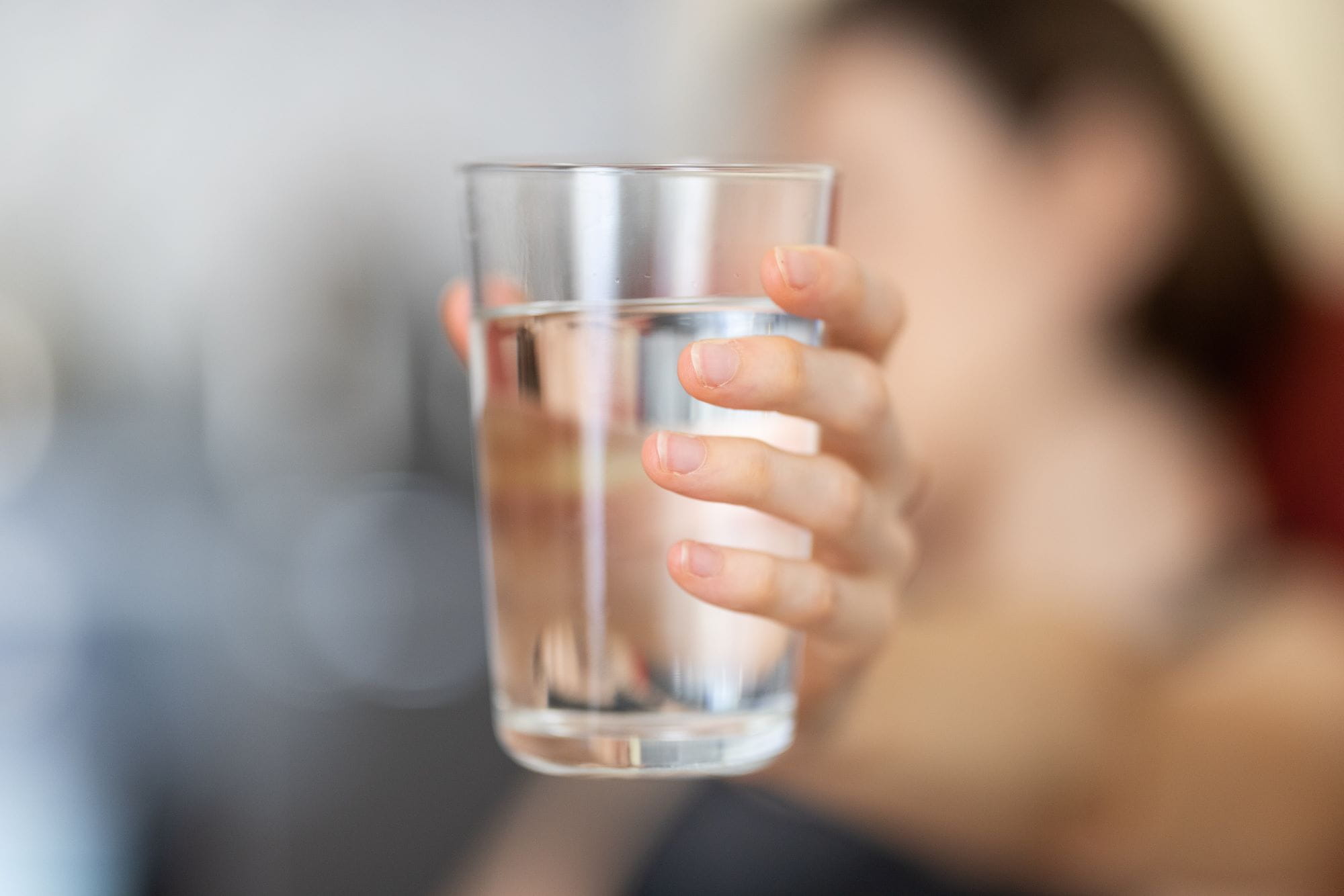person showing glass of water, focus on glass of water