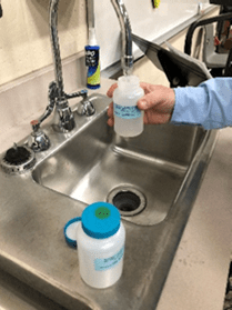 person taking water samples from large sink