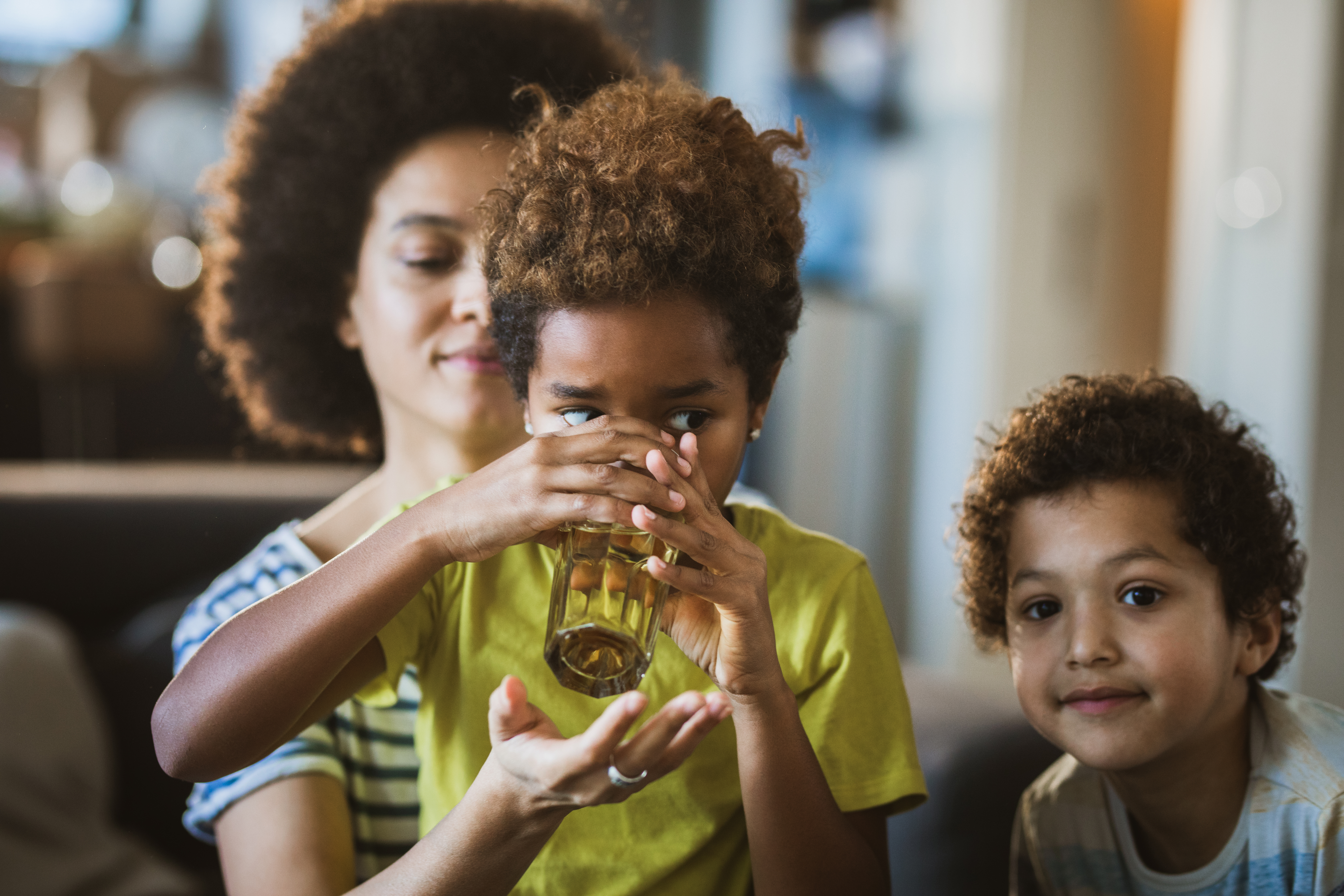 mother and her children drinking water out of glass