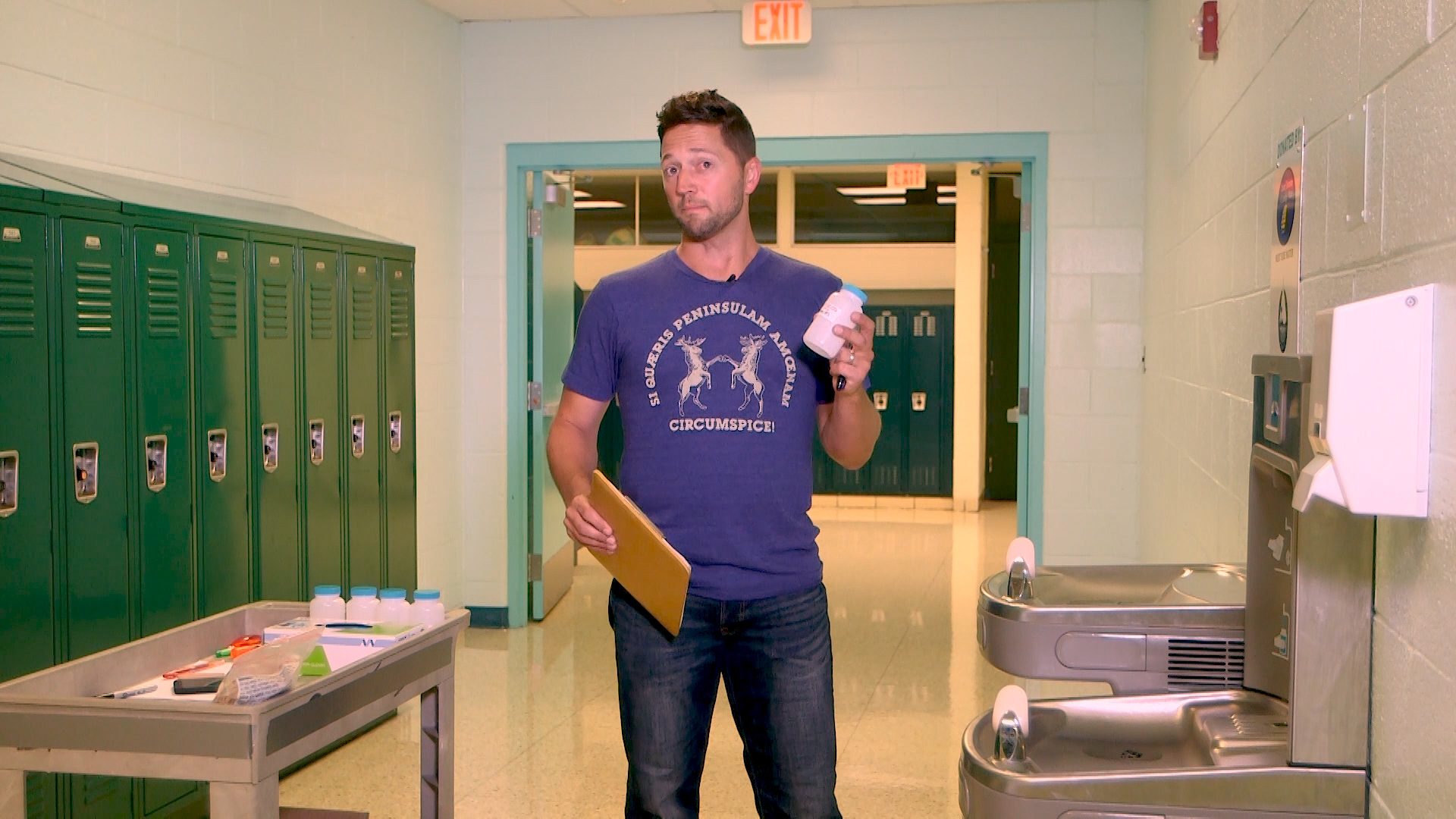 man holding sampling bottle next to school drinking water bottle filling stations