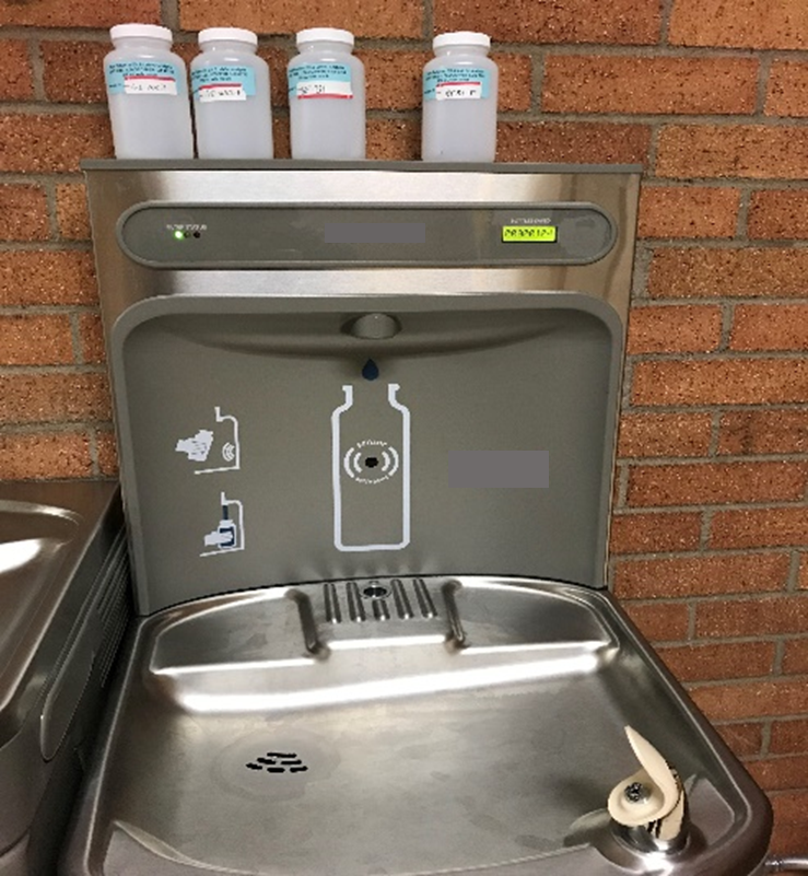 school water bottle filling station with sampling bottles on top