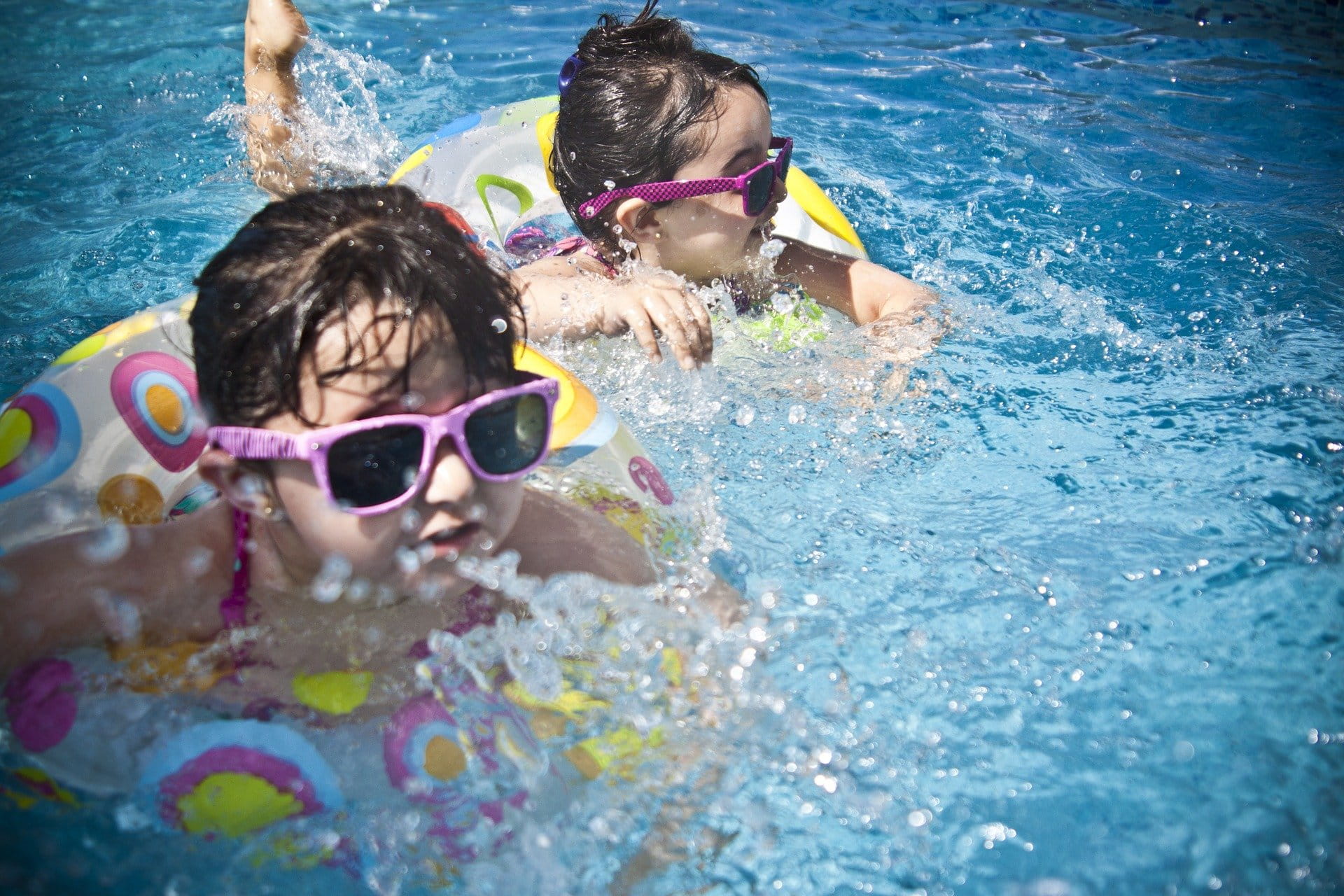 two girls swimming in pool, laughing