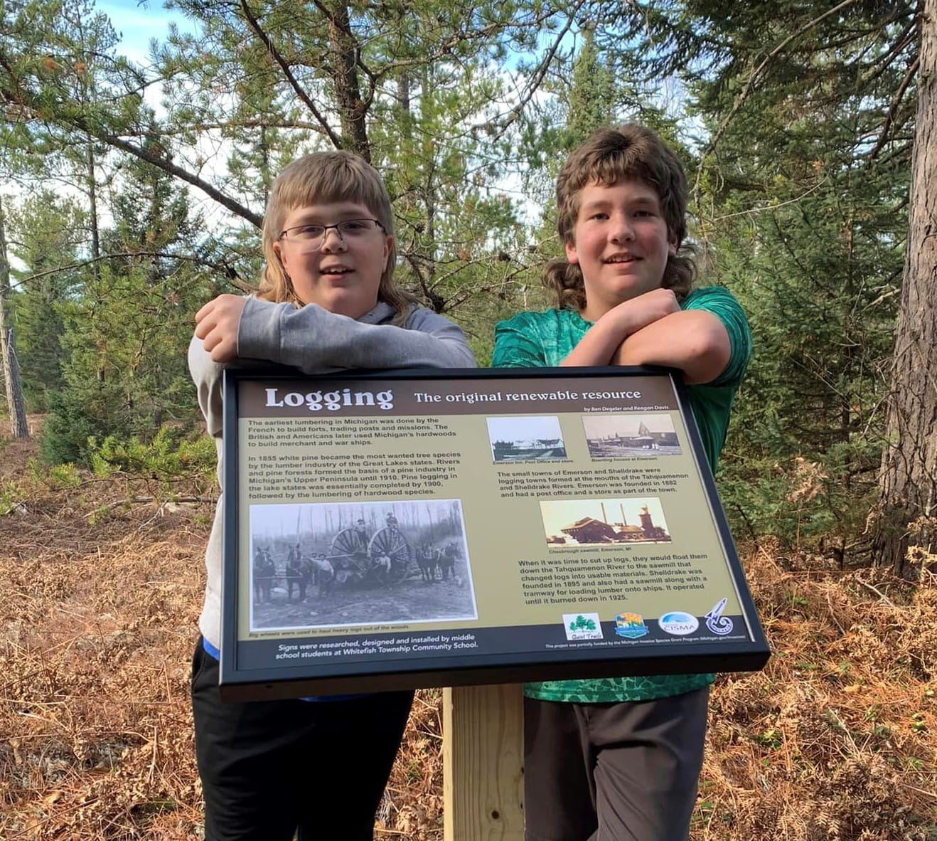 Ben Degeler, left, and Keagan Davis stand behind the "Logging-The Original Renewable Resource" sign.
