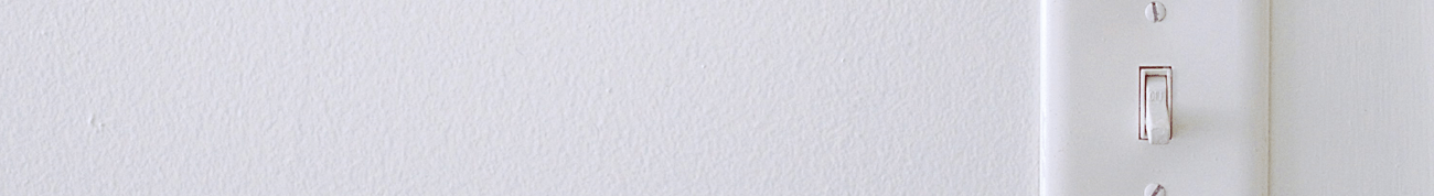A white light switch on a white wall