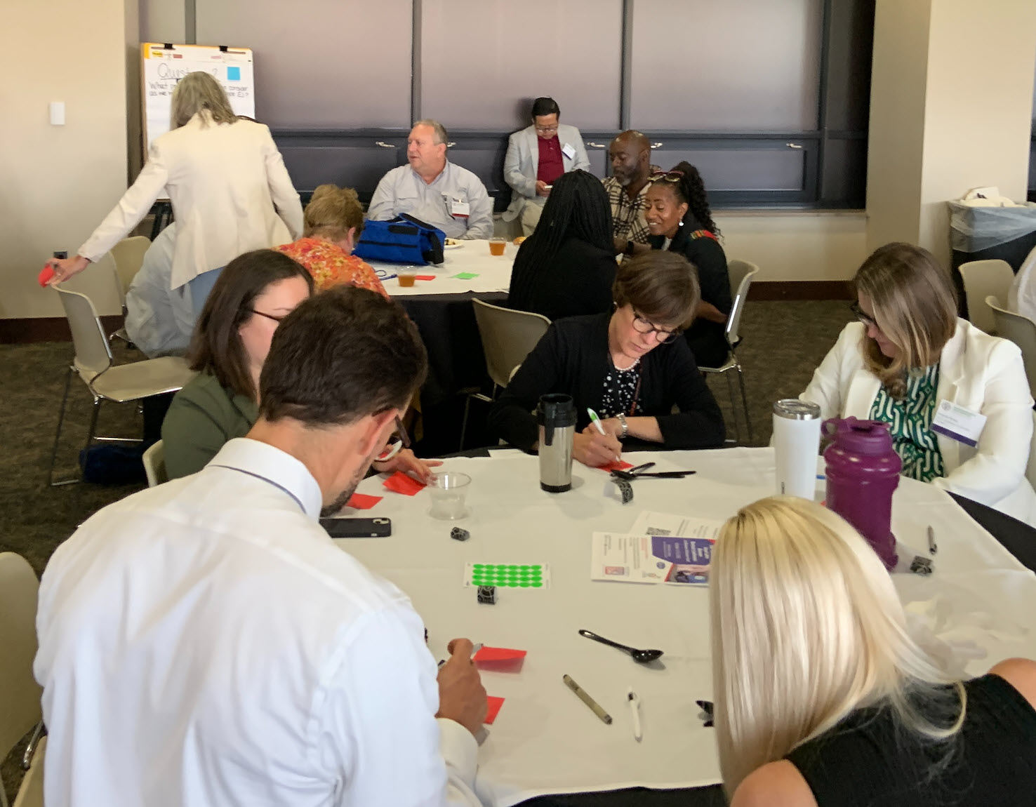 people at round conference tables with post its and posters, collaborating