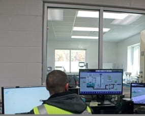 person at water treatment plant in front of laptop