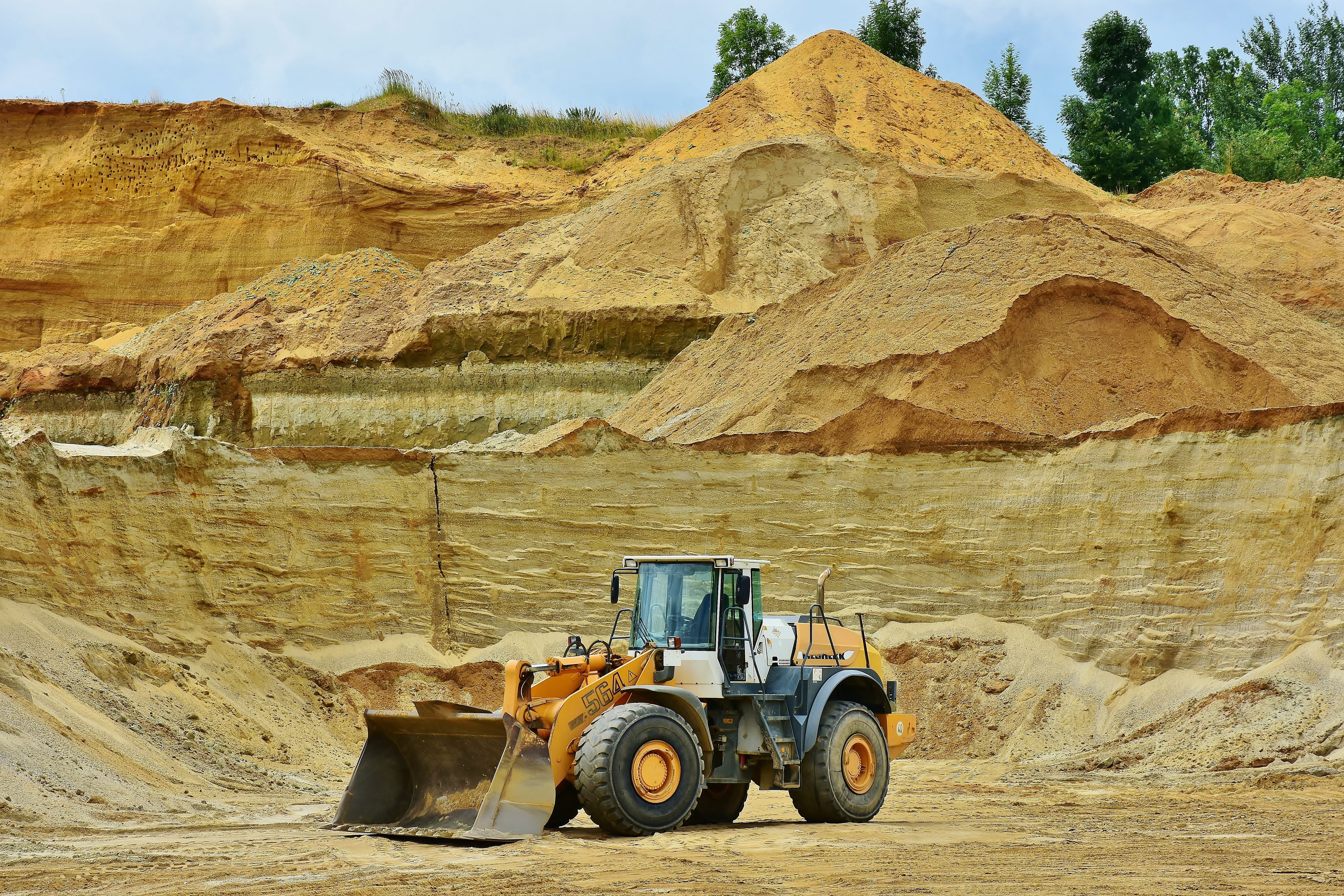 A yellow front-end loaded sits in the basin of a sandy mining area