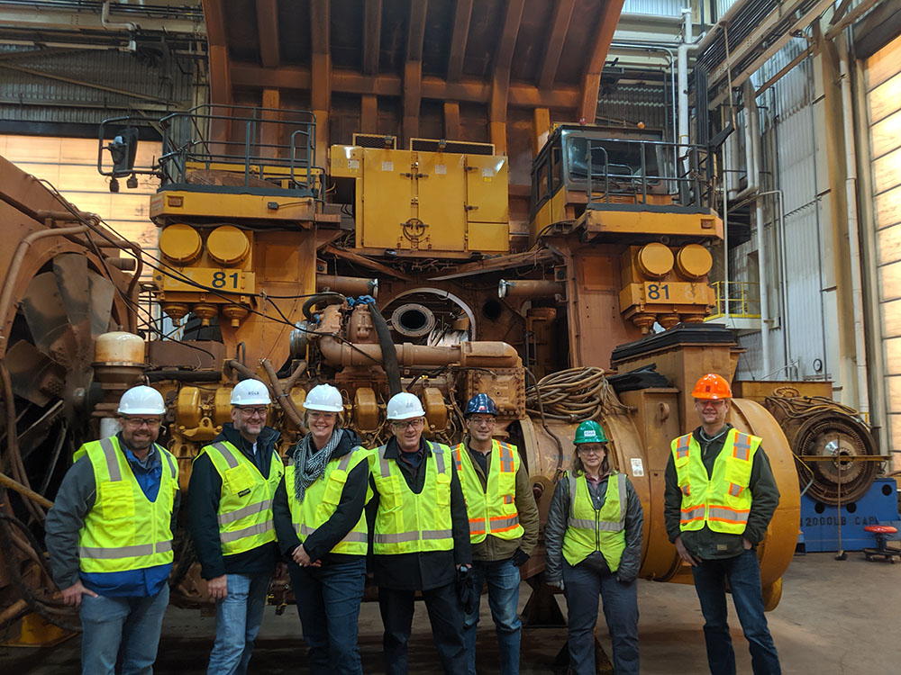 A group of EGLE staff standing in front of large mining equipment