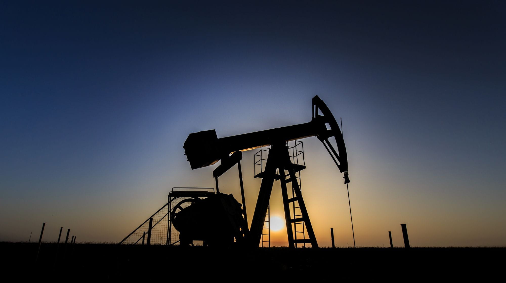 Operating oil and gas well profiled on sunset sky