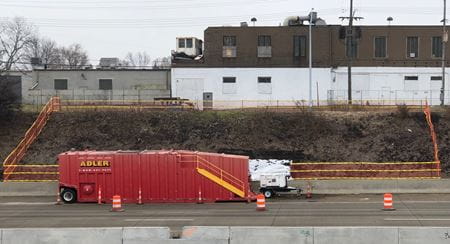 a highway embankment with orange fencing sectioning off the cleanup area with truck in foreground