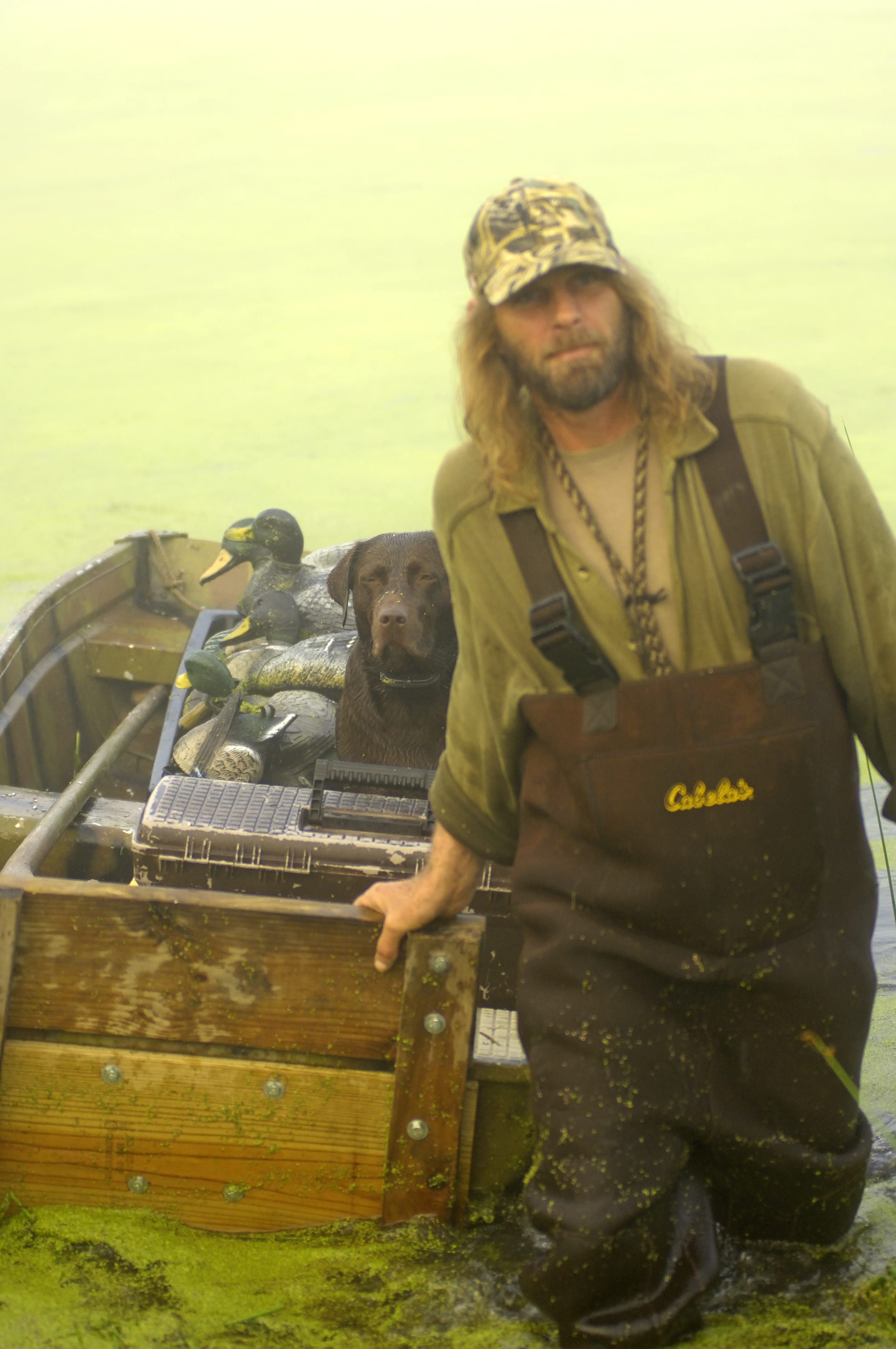 Man deploys decoys with his chocolate lab in preparation of a duck hunt. Courtesy DNR.