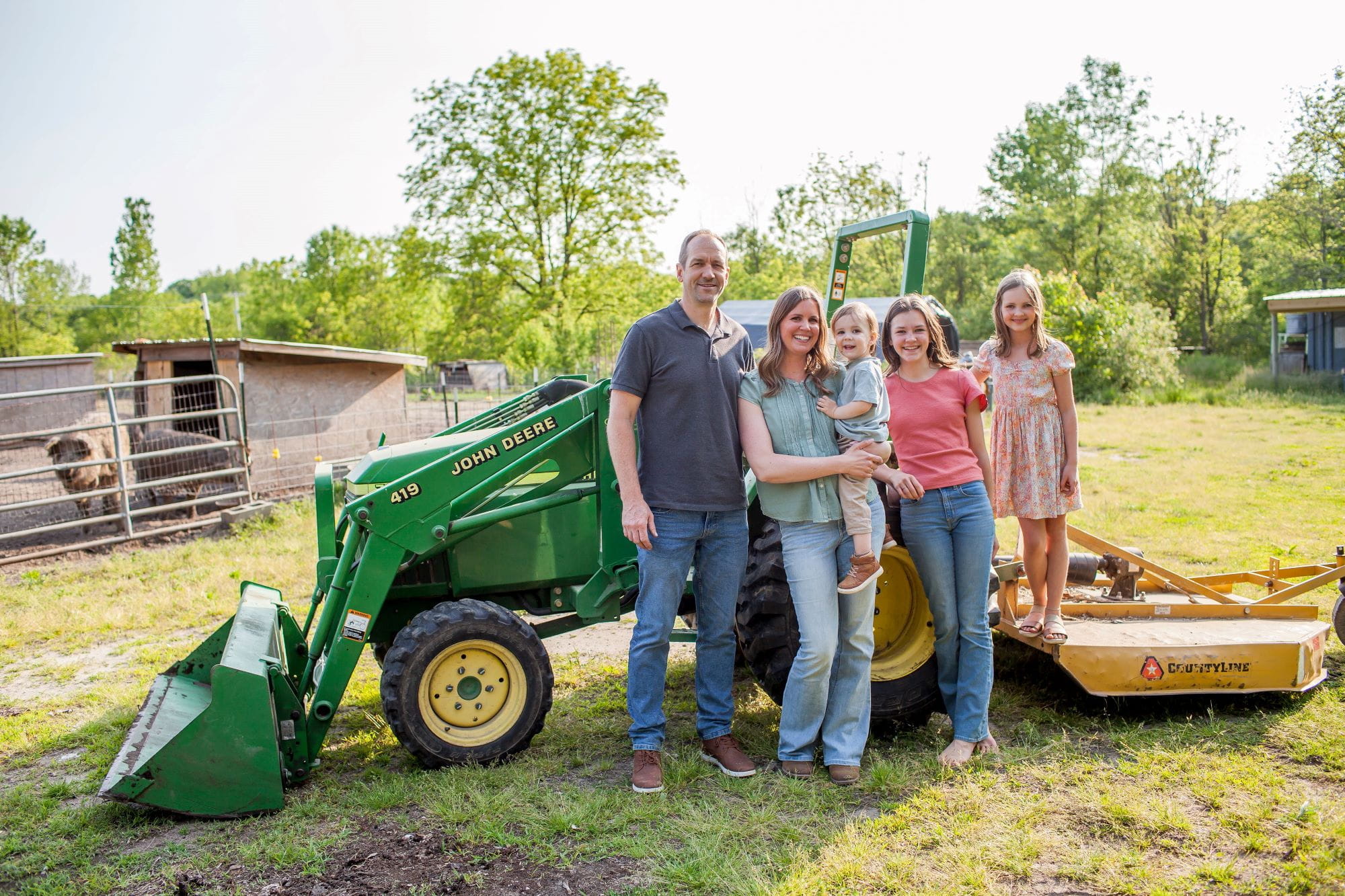 The Malski family, of Grand Rapids Compost, pose in front of a green tractor. 