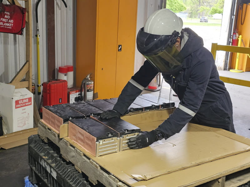 GLR staffer wearing black work gloves dismantles a battery pack for reuse testing. Credit: NextCycle Michigan.