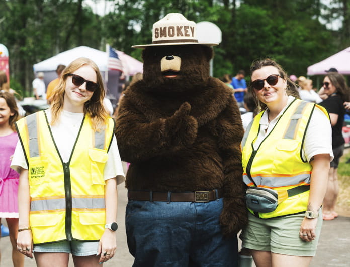 Grace Freed (left), Smokey Bear, and a third person at the grand reopening of the Little Trout Lake Park in Marquette County. Credit: Grace Freed.