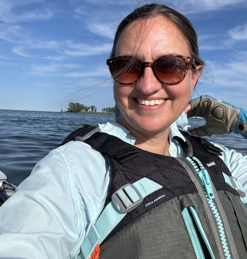 Gillian Gainsley wearing a personal flotation device while seated in a kayak on a river.