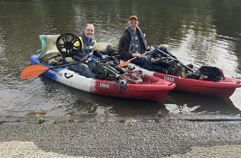 Two people in kayaks filled with trash