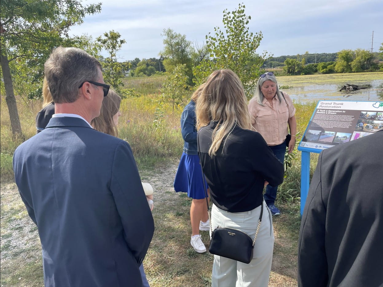 EGLE Director Phil Roos listens as Kathy Evans describes the restoration of a former dumping ground in the delisted Muskegon Lake Area of Concern.