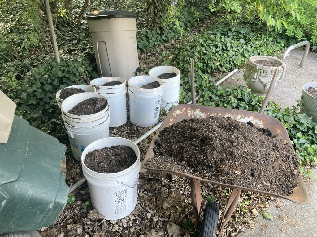 Buckets and a wheelbarrow filled with compost.
