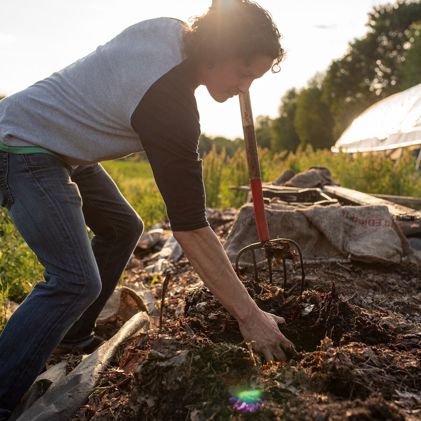 Luis Chen of Wormies turns compost with a pitchfork.