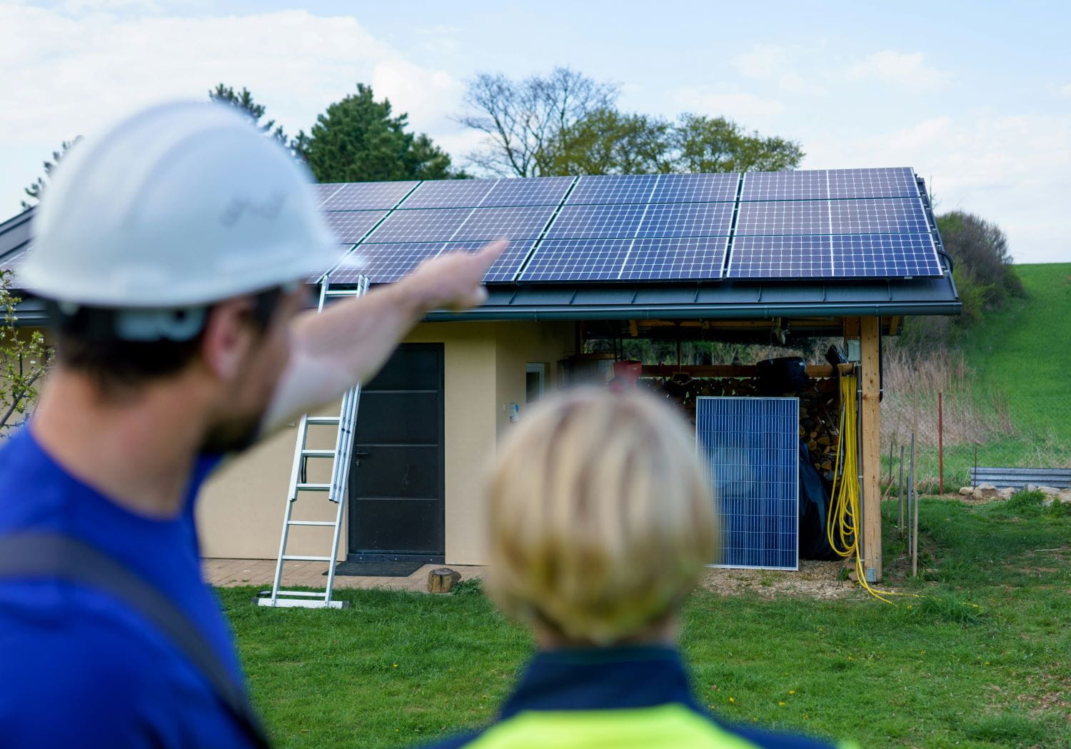 A solar installation expert gestures towards a solar panel in front of a small one story home