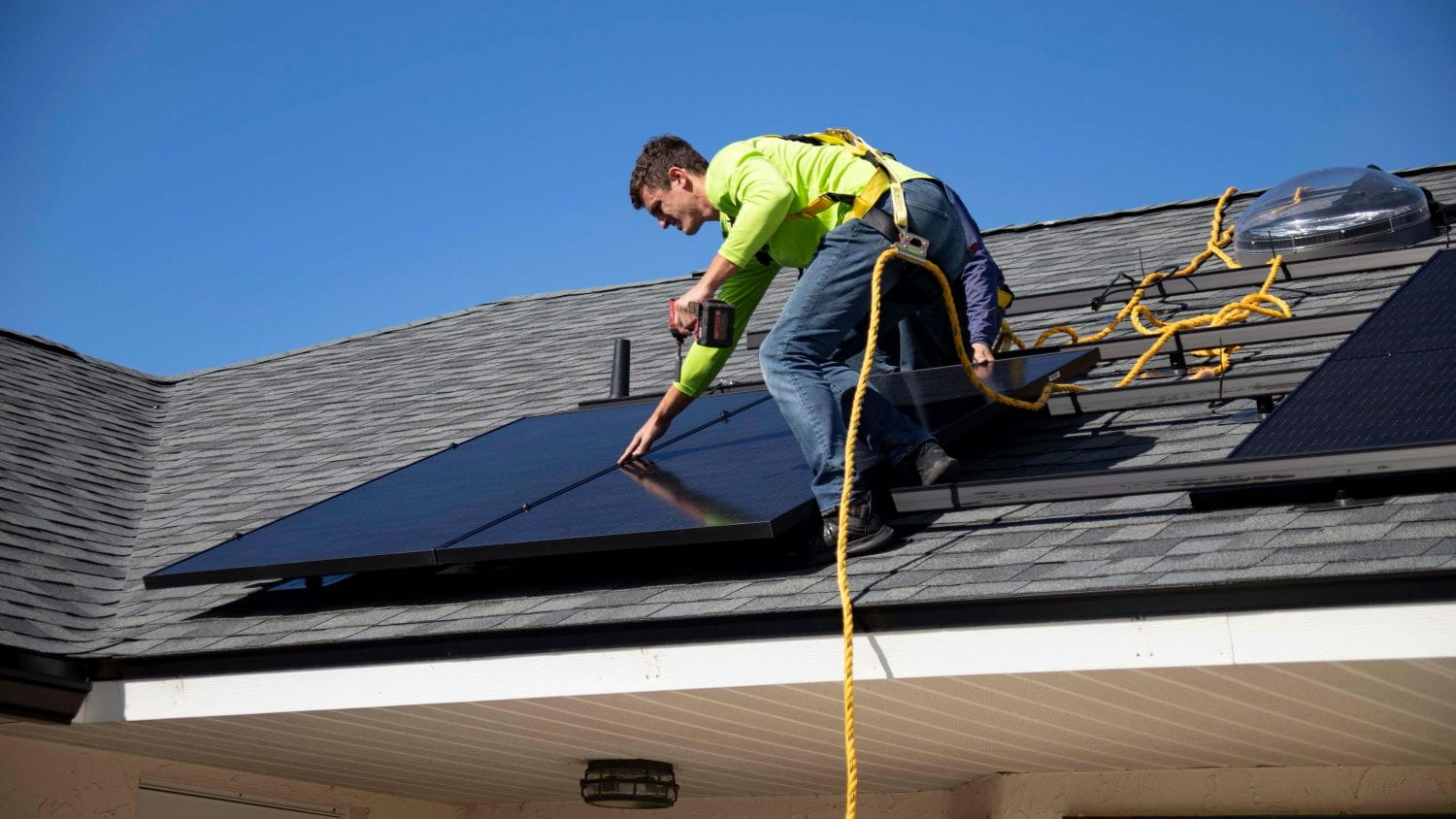 A construction worker on the roof of a residential home installing a solar panel