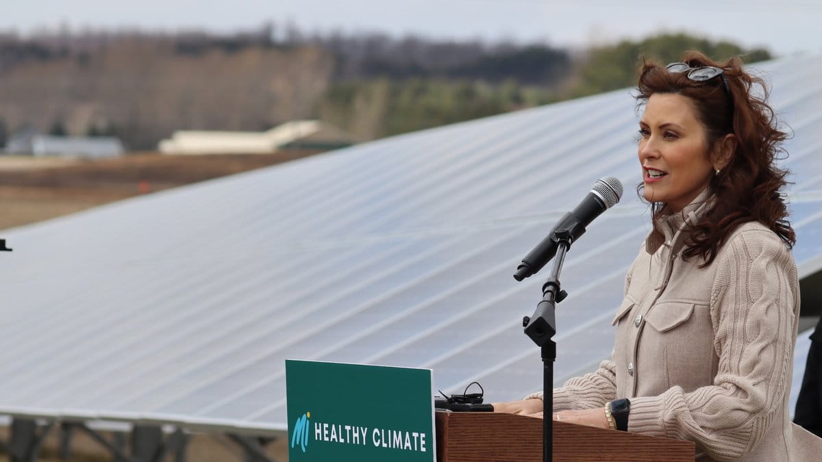 Governor Gretchen Whitmer at lectern with MI Healthy Climate Plan sign and a solar panel in the background.