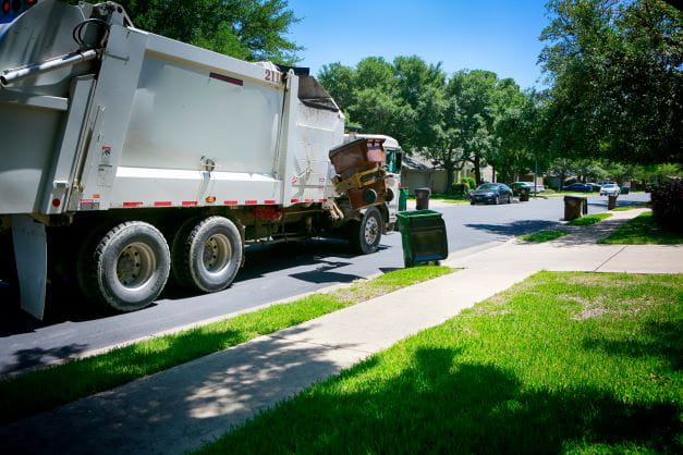 A garbage truck among piles of trash.